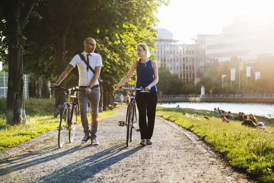 Germany, Berlin, Man and woman walking with bicycles in city