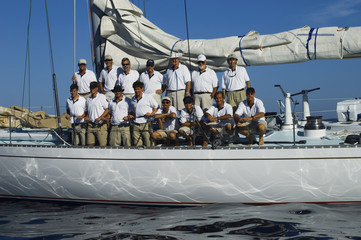 Sailing crew posing for a group portrait on board against clear blue sky
