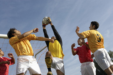 Low angle view of young players playing soccer against sky