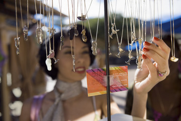 Woman choosing pendent chain in outdoor market