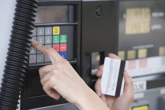 Close-up of woman's hand using ATM machine at fuel station