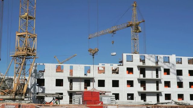 The construction of an apartment residential complex. Builders put the brickwork. Construction crane provides supplying the cement for the builders