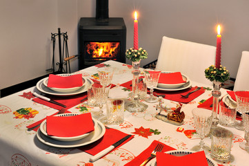 Beautiful new year table with red napkin Wood burning stove on background