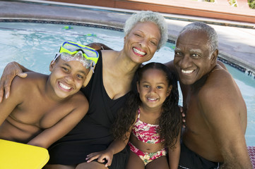 Portrait of a girl and boy with grandparents by the swimming pool