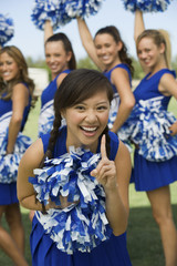 Portrait of an excited young cheerleader gesturing with friends in background