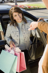 Happy mature woman with shopping bags coming out of a car