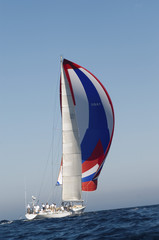 Side shot of a yacht in the ocean with full sail against the clear sky