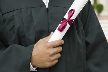 Midsection closeup of young male student holding diploma on graduation day
