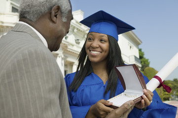 Happy young graduate student receiving gift from her father