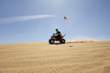 Side view of a man riding quad bike in desert on a sunny day