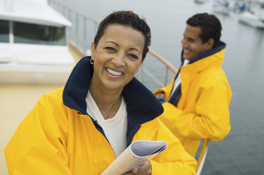 Portrait Of Happy Woman Holding A Book With Man In Background On The Yacht