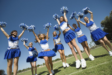 Fototapeta na wymiar Group of excited young cheerleaders cheering on field