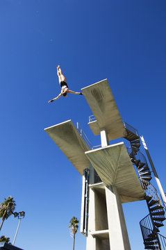 Low angle view of a male swimmer diving in midair from the springboard