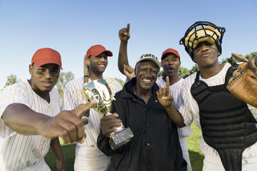 Portrait of baseball team and coach with trophy celebrating victory outdoors