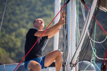 Fototapeten Yachtsman pulls the rope controlling the sail on sailing boat. © De Visu