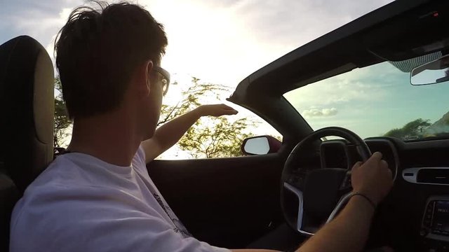 CLOSEUP: Happy man traveling around the tropical island in convertible at sunset