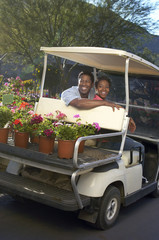 Happy African American couple in golf cart at botanical garden