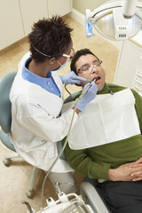 Naklejka na ściany i meble High angle view of female dentist treating male patient at clinic