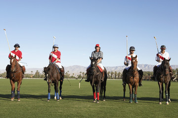 Polo players and umpire mounted on horses on field