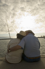 Rear view of romantic senior couple fishing at the beach