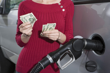 Mid section of a middle aged woman refueling her car at a fuel station