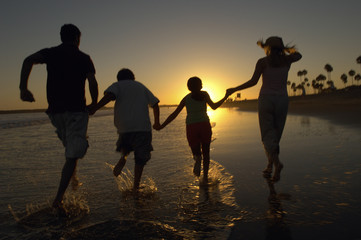Rear view of family holding hands and running on the beach
