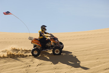 Side view of young man riding quad bike in desert © MDBPIXS