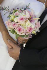 Bride and Groom holding hands and bouquet (close-up)