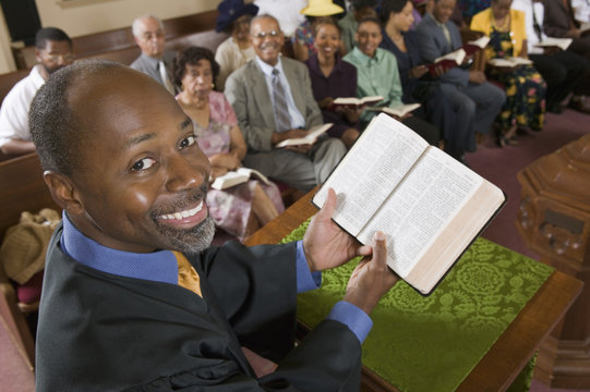 Preacher at altar holding open Bible in Front of Congregation portrait high angle view