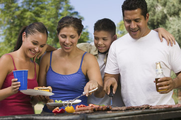 Boy with family gathered around the grill at picnic