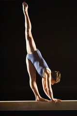 Female gymnast striking pose on balance beam