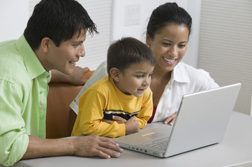 Happy young couple with son using laptop at desk