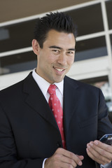 Fototapeta premium Portrait of happy Asian businessman holding mobile phone