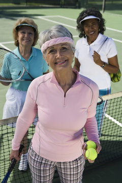 Happy senior woman with female friends at tennis court