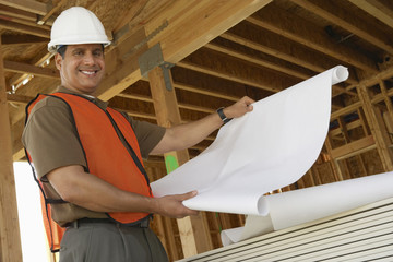 Portrait of a smiling construction worker with blueprints