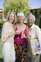 Naklejka premium Portrait of three multiethnic women standing together with glass of champagne at lawn