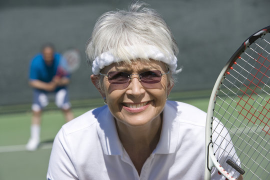 Portrait of happy senior woman playing tennis