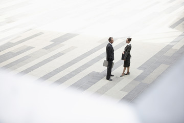 High angle view of businessman and businesswoman standing in outdoor plaza