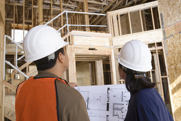 Rear view of female engineer and co-worker at constructions site