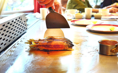 Chef fried fishs in a teppanyaki kitchen.