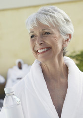 Fototapeta na wymiar Smiling senior woman wearing bathrobe in dayspa