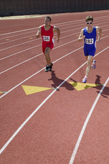 Obraz premium Two male athletes running on race track