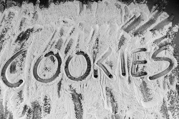 Word cookies written in flour on table