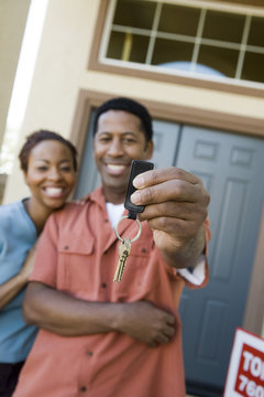 Happy African American couple holding a pair of keys of their new house