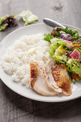 Italian salad with rotisserie chicken and white rice on dark wood
