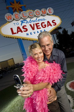 Happy mature couple taking self portrait through mobile phone with 'Las Vegas' sign in the background