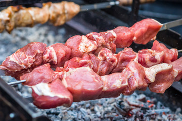 raw meat on skewers cooked on fire