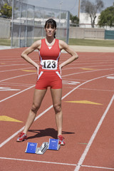 Obraz premium Full length of confident female athlete at starting block on race track