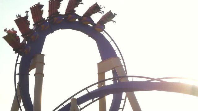 CLOSE UP: People riding upside down rail looping roller coaster