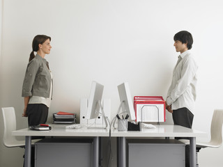 Side view of business people standing at computer desks facing each other